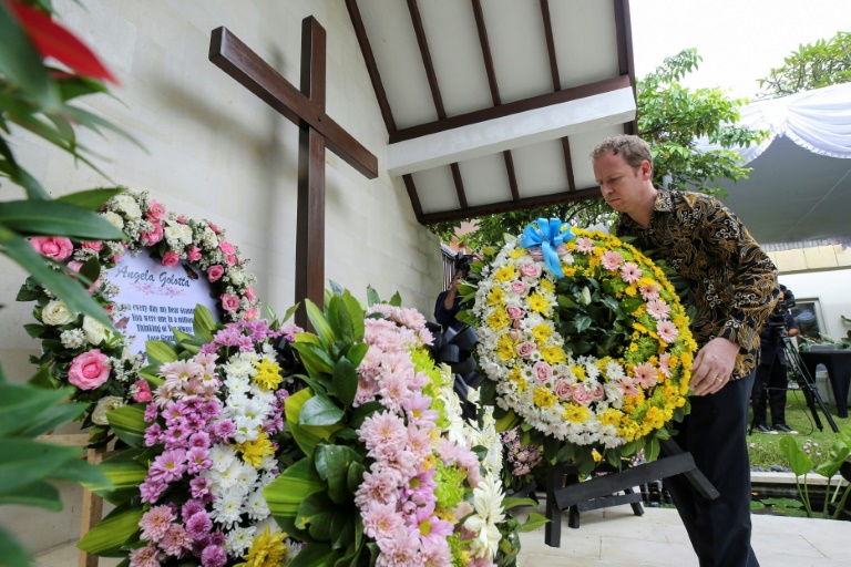 O rudă a unei victime depune o coroană de flori în fața Consulatului Australian din Denpasar, Indonezia, în timpul comemorărilor care marchează cea de-a 20-a aniversare a atentatului de la Bali, 12 octombrie 2022 (POOL/AFP - FIRDIA LISNAWATI)