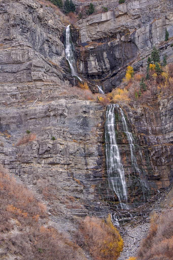 Vedere de toamnă de la Bridal Veil Water Falls Utah Provo Canyon.  Buiandrugul este vizibil pe verticală în cadrul din mijloc.  Apare ca două niveluri separate.  Rândul de sus este simplu, în timp ce rândul de jos este o cascadă dublă.  înconjurat de stânci și vegetație uscată brun-aurie